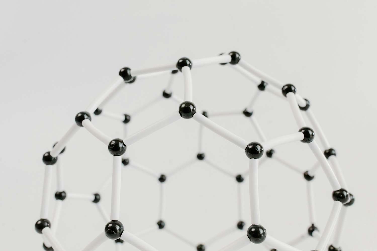 A close-up of a spherical model made of black balls and white sticks.