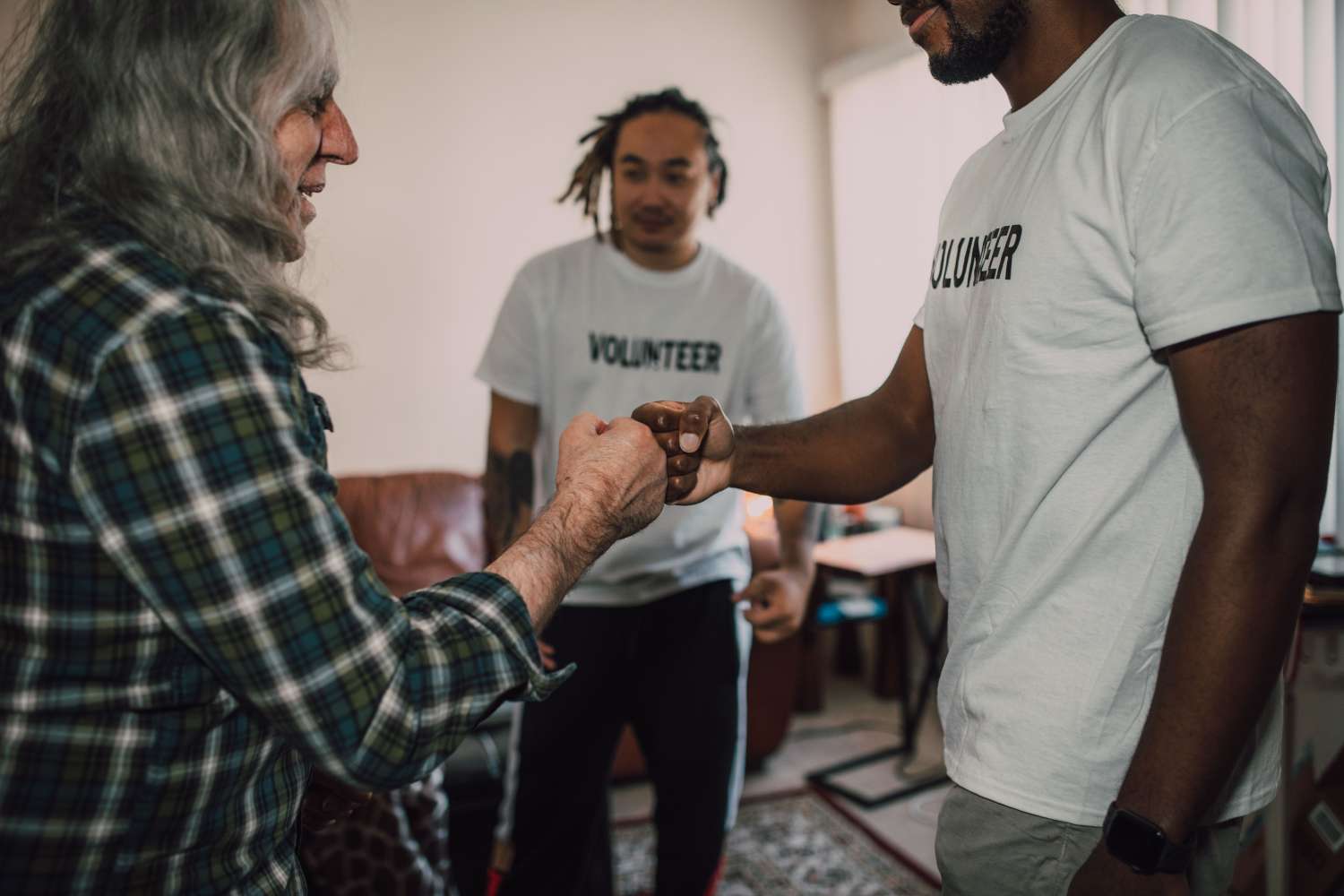 a volunteer fist bumps someone in the foreground while another volunteer stands in the background