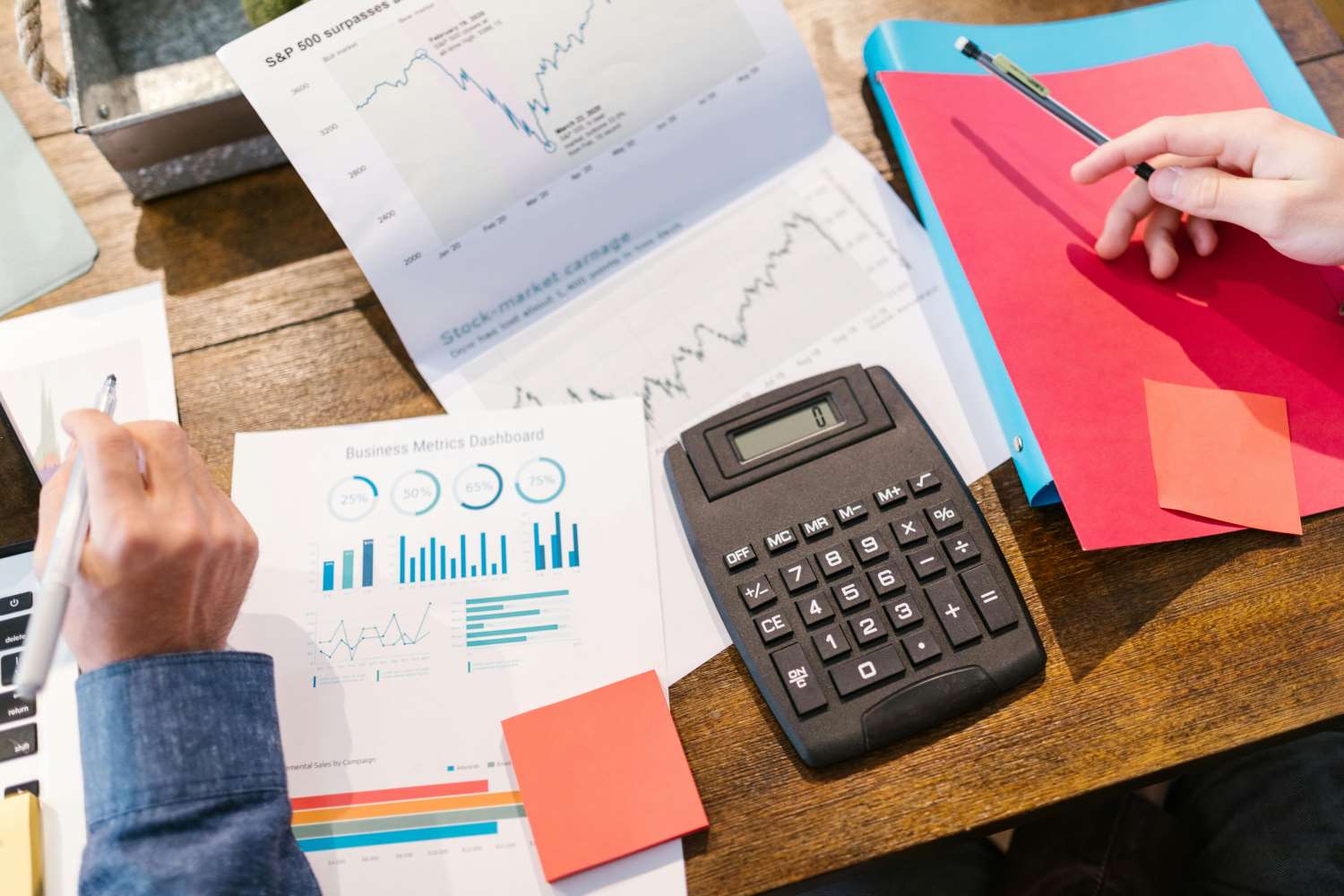 Paperwork with charts on and a calculator on a desk